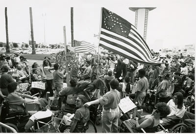 <p><strong>1. </strong>1994,  Las Vegas. ADAPT organizasyonu tarafından düzenlenmiş, çoğu tekerlekli sandalye  kullanıcısı olan kişilerin “sakat hakları ve özgürlük” mücadelesi için  yaptıkları eylem.<br />Fotoğraf: Tom Olin, www.exploregram.com/grassroots-activists-from-the-disability-rights-group-adapt-protest-in-las-vegas [Erişim: 13.11.2016]